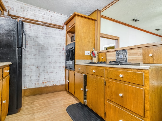 kitchen with visible vents, freestanding refrigerator, oven, light wood-style floors, and a textured ceiling