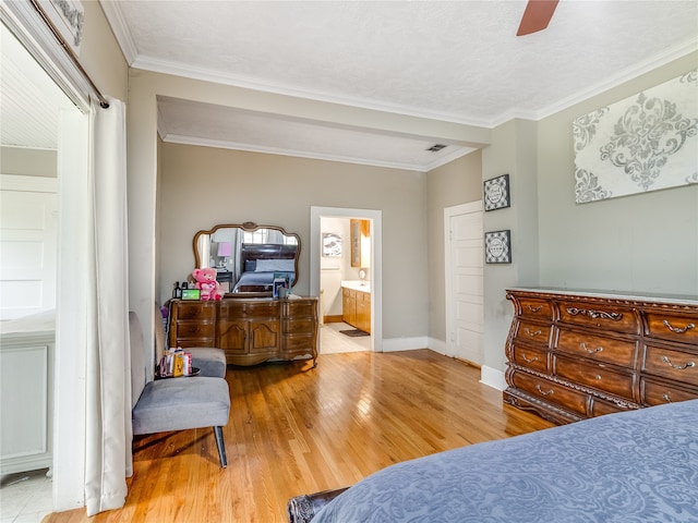 bedroom featuring crown molding, visible vents, wood finished floors, baseboards, and ensuite bathroom