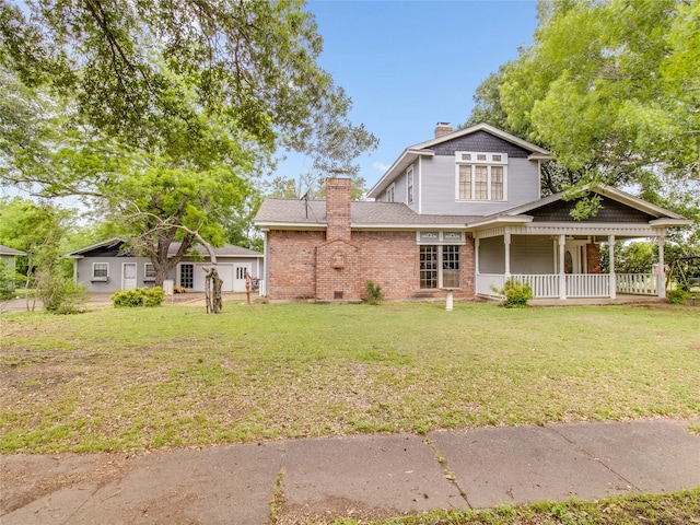 view of front facade with a chimney, a front yard, a porch, and brick siding