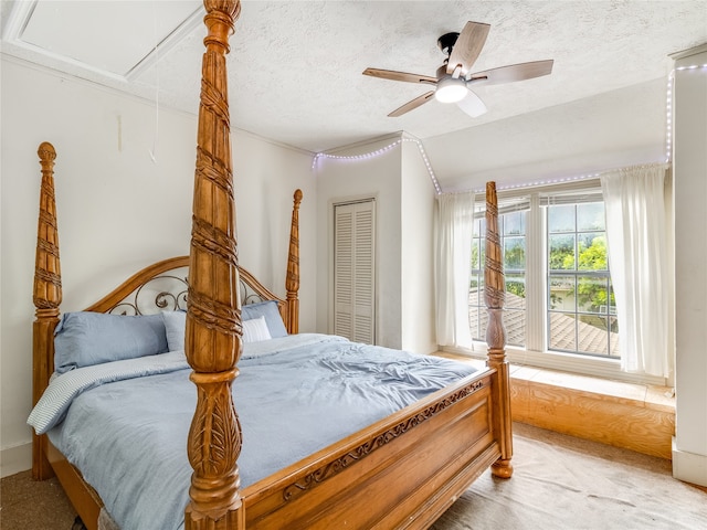 bedroom with a closet, attic access, a textured ceiling, and light colored carpet
