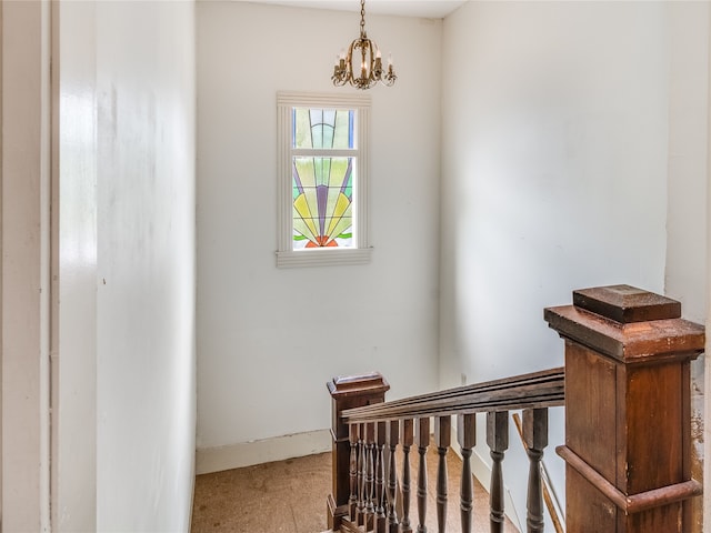 stairway featuring baseboards and a notable chandelier