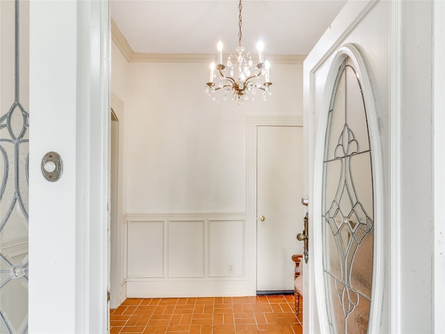 entryway featuring crown molding, a decorative wall, a chandelier, and a wainscoted wall