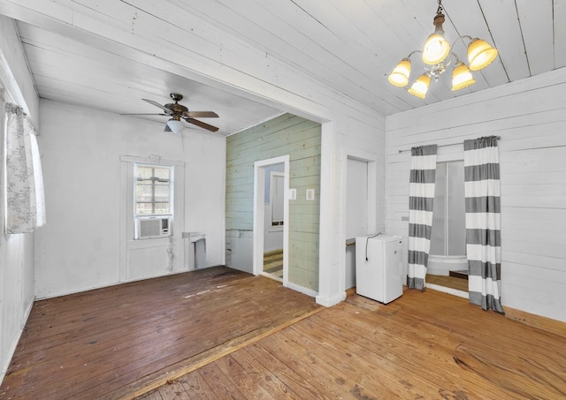 interior space with wood-type flooring, wooden walls, ceiling fan with notable chandelier, and cooling unit