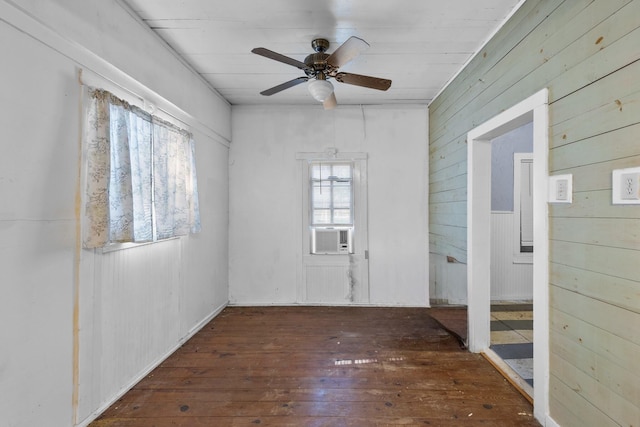 unfurnished room featuring wood-type flooring, a ceiling fan, wood walls, and cooling unit