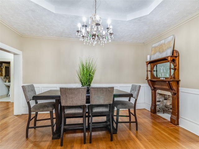 dining room featuring an inviting chandelier, a wainscoted wall, a tray ceiling, and wood finished floors