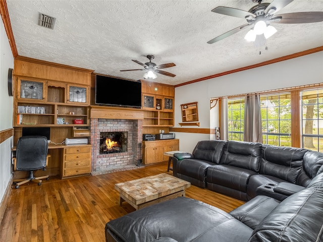 living room with visible vents, a ceiling fan, wood-type flooring, and a textured ceiling