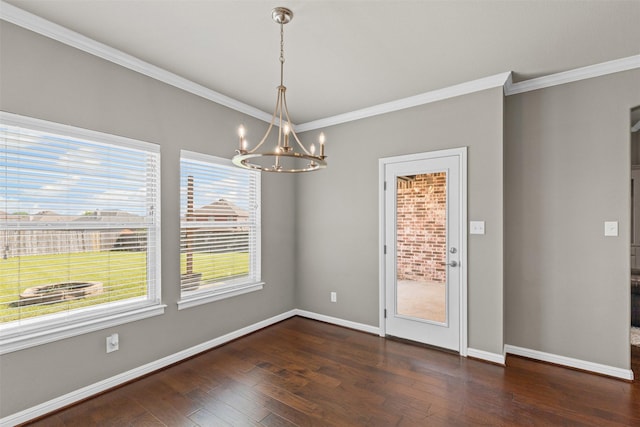 unfurnished dining area featuring an inviting chandelier, hardwood / wood-style flooring, crown molding, and baseboards