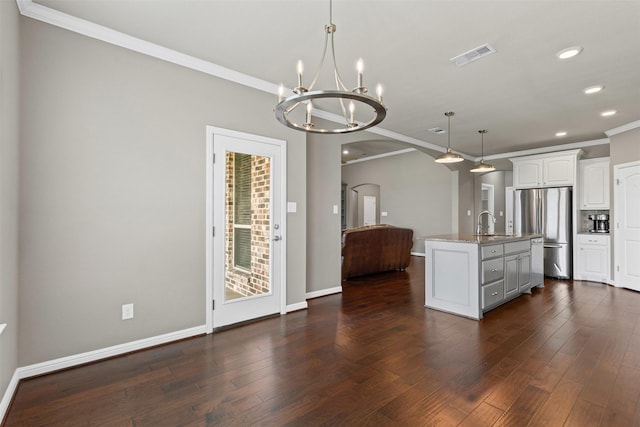 kitchen featuring recessed lighting, arched walkways, an inviting chandelier, freestanding refrigerator, and ornamental molding