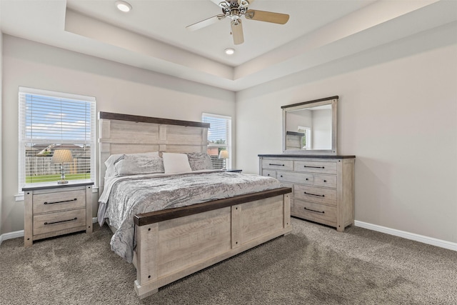 carpeted bedroom featuring recessed lighting, a tray ceiling, a ceiling fan, and baseboards