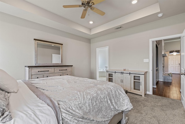 carpeted bedroom featuring baseboards, visible vents, a tray ceiling, and recessed lighting