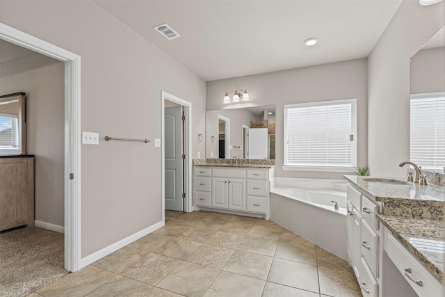 full bathroom featuring a bath, two vanities, a sink, and visible vents