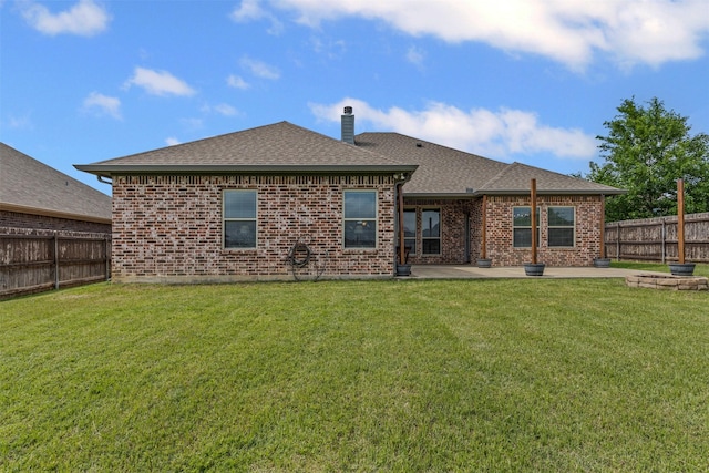 rear view of house with brick siding, roof with shingles, a fenced backyard, and a patio area