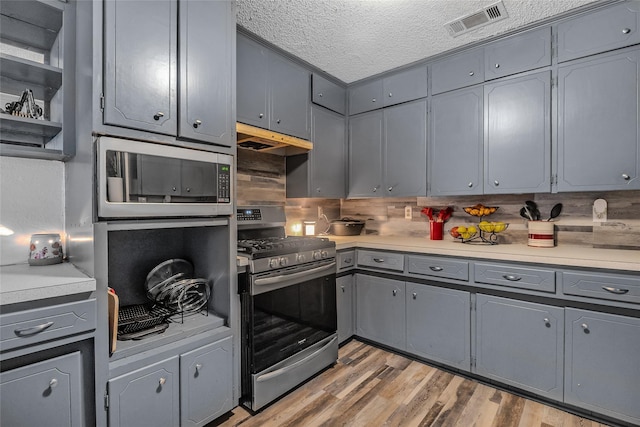 kitchen featuring gray cabinets, a textured ceiling, visible vents, appliances with stainless steel finishes, and under cabinet range hood