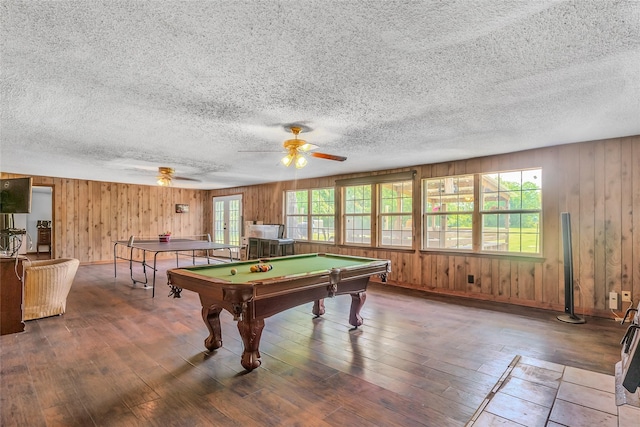 game room featuring wooden walls, wood finished floors, and a healthy amount of sunlight