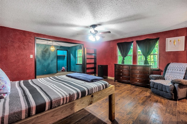 bedroom featuring wood-type flooring, a textured ceiling, a textured wall, and a ceiling fan
