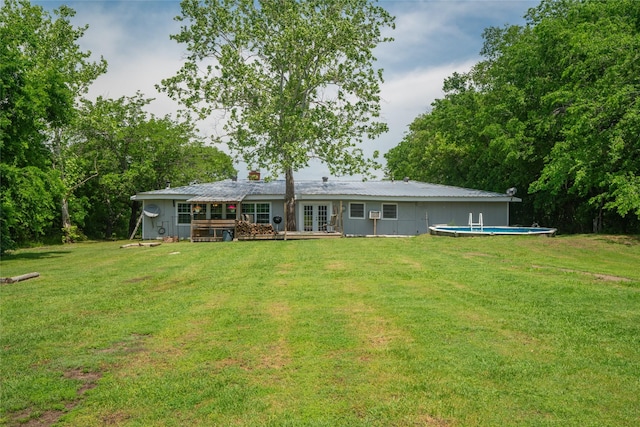 rear view of house featuring a lawn, an outdoor pool, a wooden deck, and french doors