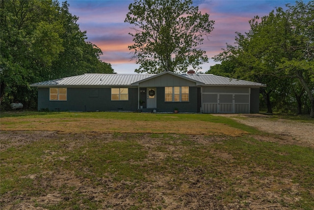 ranch-style house featuring a yard, driveway, and metal roof