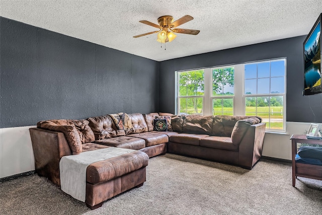living room with a ceiling fan, a textured ceiling, a textured wall, and carpet