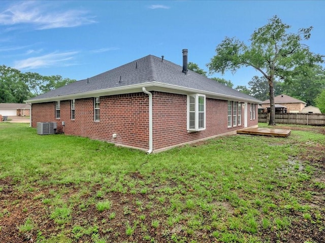 view of property exterior with central air condition unit, a wooden deck, a yard, brick siding, and fence