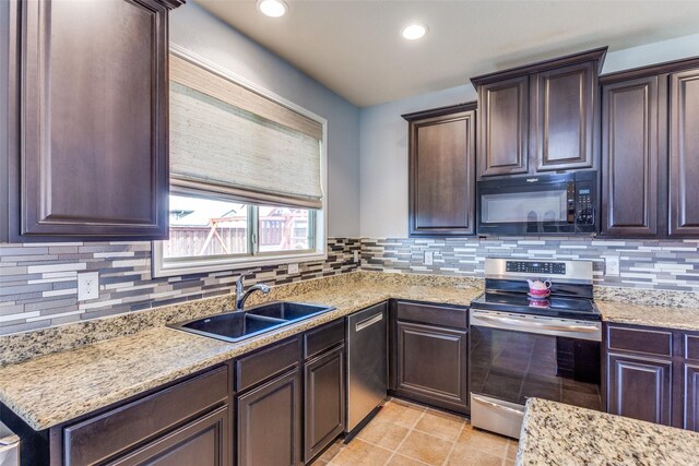 kitchen with appliances with stainless steel finishes, a sink, dark brown cabinetry, tasteful backsplash, and recessed lighting
