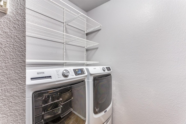 laundry area featuring washing machine and dryer and a textured wall