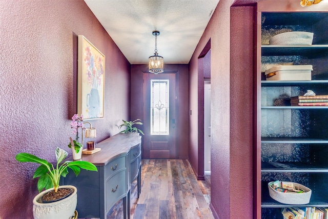 doorway with a textured wall and wood finished floors