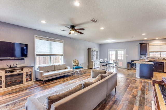 living area with recessed lighting, a ceiling fan, wood-type flooring, and a textured ceiling