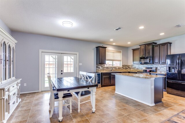 kitchen with black appliances, french doors, dark brown cabinets, backsplash, and a center island