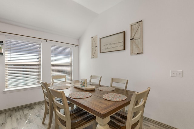 dining room with light wood-style floors and vaulted ceiling