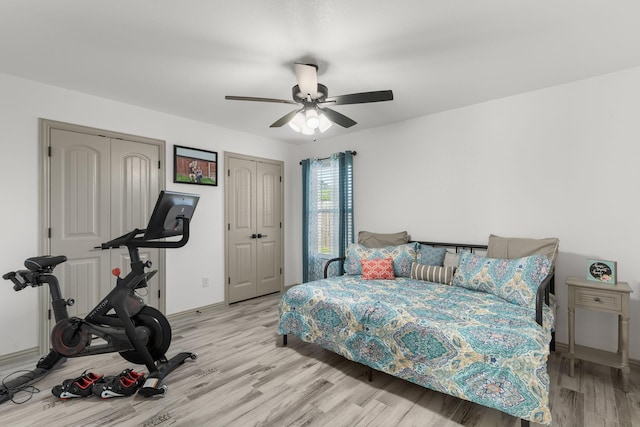 bedroom featuring wood finished floors, multiple closets, and a ceiling fan