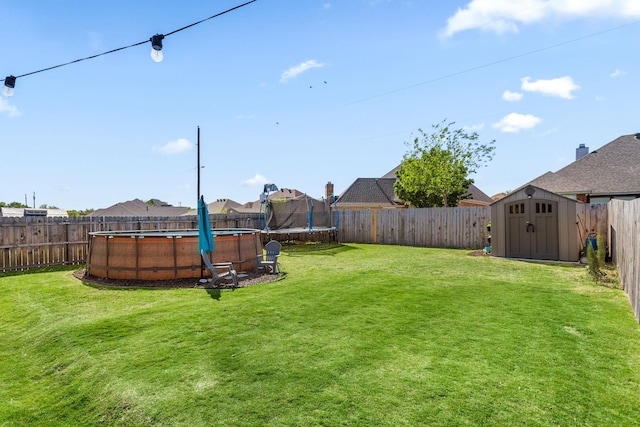 view of yard with a trampoline, an outdoor structure, a residential view, a fenced backyard, and a storage unit