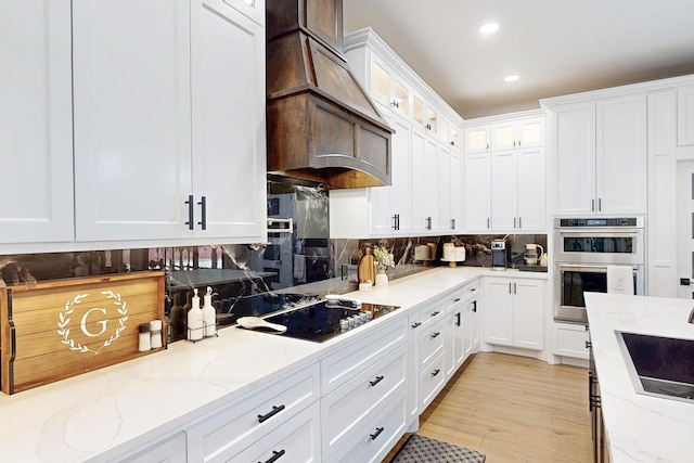 7401 Retta Mansfield Rd, Mansfield, TX 76063 - kitchen featuring stainless steel double oven, black electric cooktop, a sink, light stone counters, and white cabinetry