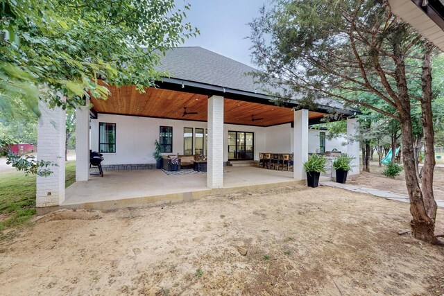 rear view of house featuring brick siding, a patio, ceiling fan, and roof with shingles