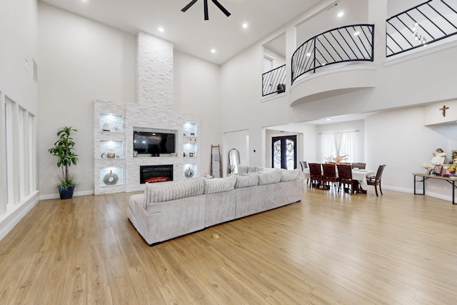 living room featuring wood finished floors, ceiling fan, a high ceiling, and a fireplace