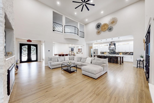 living room featuring recessed lighting, a high ceiling, ceiling fan, and light wood finished floors