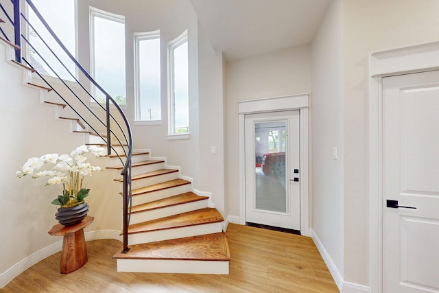 foyer with baseboards, light wood-style flooring, stairs, and a wealth of natural light