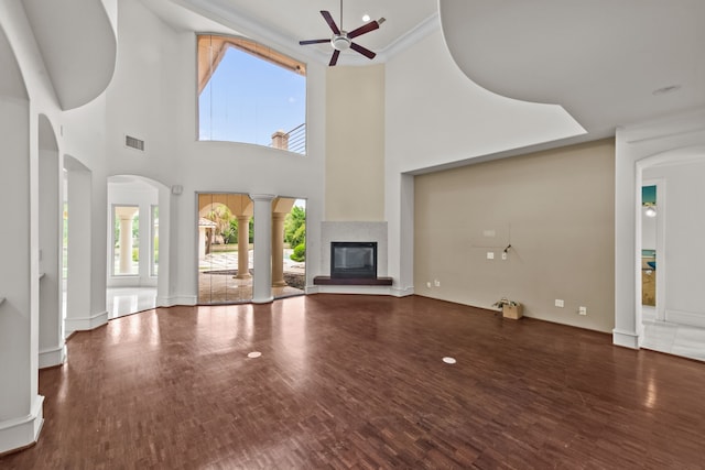 unfurnished living room with visible vents, a ceiling fan, a glass covered fireplace, and wood finished floors