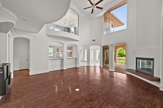 unfurnished living room featuring a glass covered fireplace, ceiling fan, wood finished floors, and a healthy amount of sunlight