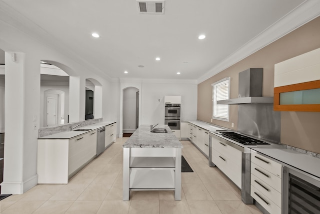 kitchen featuring visible vents, modern cabinets, a sink, wine cooler, and wall chimney exhaust hood