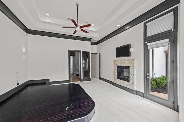 unfurnished living room featuring recessed lighting, a raised ceiling, a glass covered fireplace, and ceiling fan