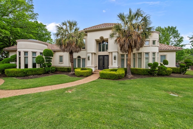 view of front of property with french doors, a tile roof, a front yard, and stucco siding
