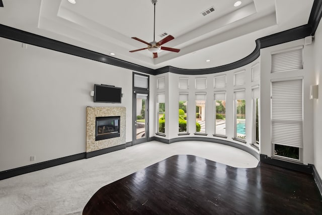 unfurnished living room featuring visible vents, ceiling fan, recessed lighting, a high end fireplace, and a raised ceiling
