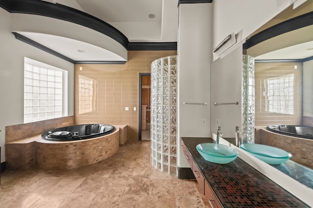 bathroom featuring crown molding, vanity, a garden tub, and tile walls