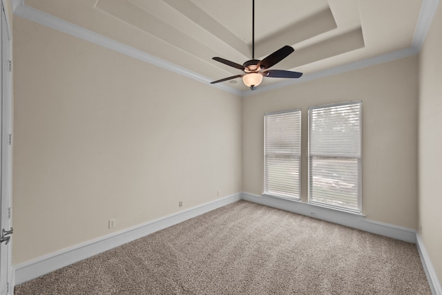 spare room with crown molding, baseboards, ceiling fan, a tray ceiling, and carpet