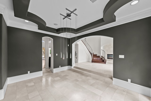 interior space with baseboards, stairway, recessed lighting, a raised ceiling, and arched walkways