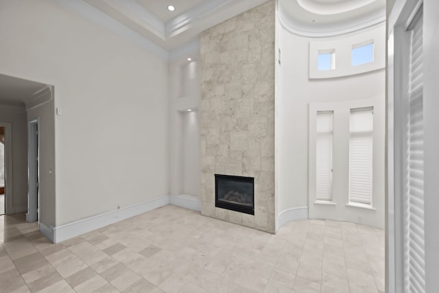unfurnished living room featuring baseboards, a high end fireplace, and a towering ceiling