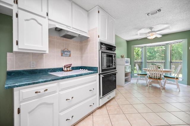 kitchen with multiple ovens, visible vents, white cooktop, dark countertops, and white cabinets