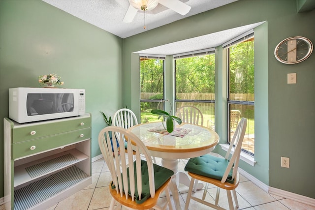 dining space with tile patterned floors, baseboards, ceiling fan, and a textured ceiling