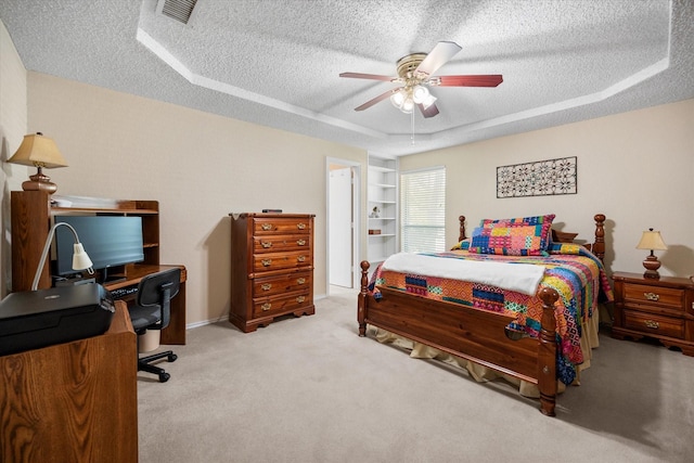 bedroom with a raised ceiling, a ceiling fan, visible vents, carpet, and a textured ceiling