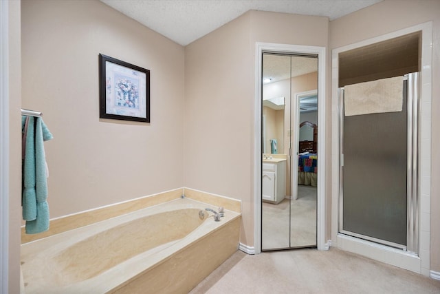 ensuite bathroom featuring a garden tub, a stall shower, a textured ceiling, and ensuite bathroom